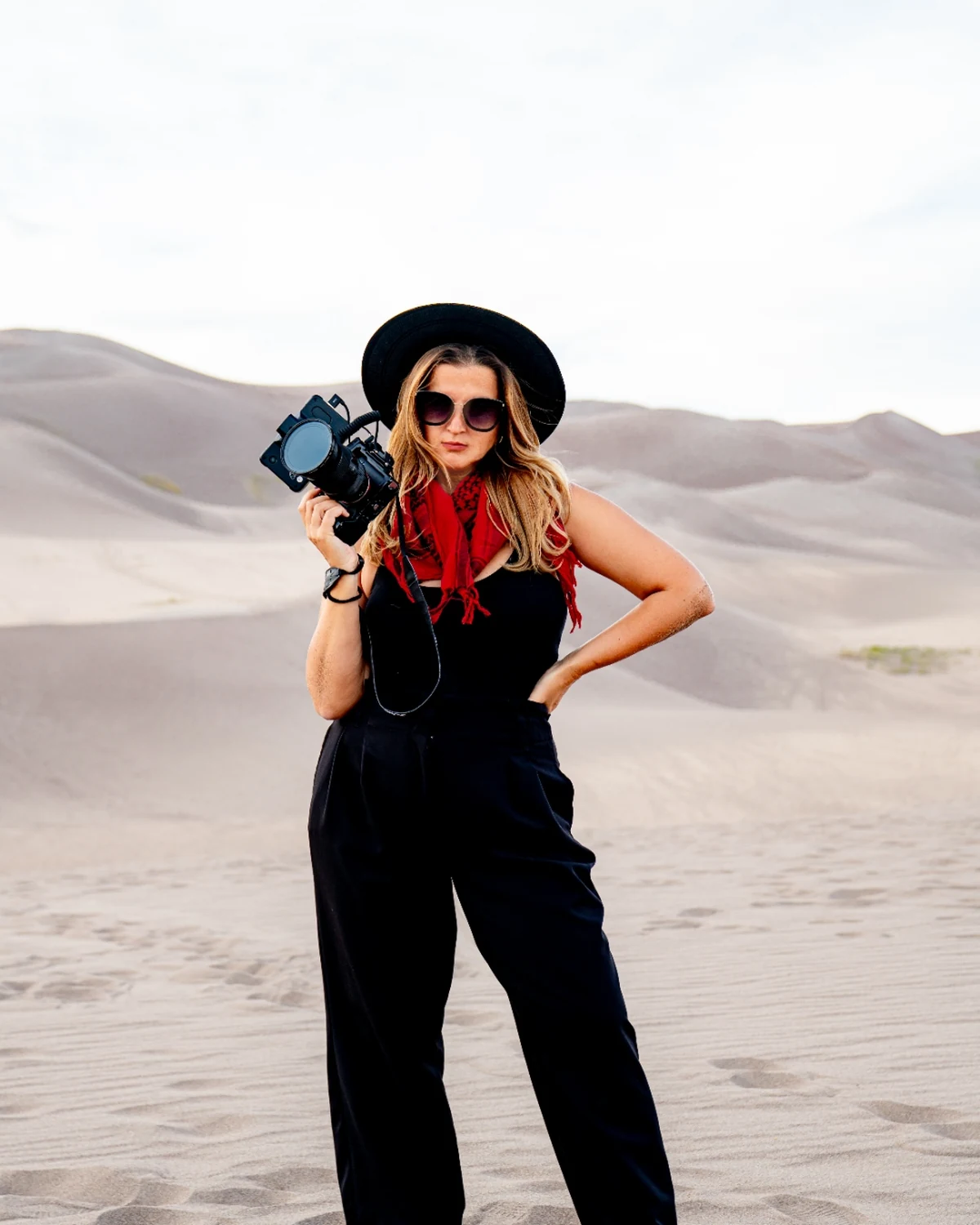 Kadri Bennett on the Great Sand Dunes at golden hour, cinema camera raised in one hand